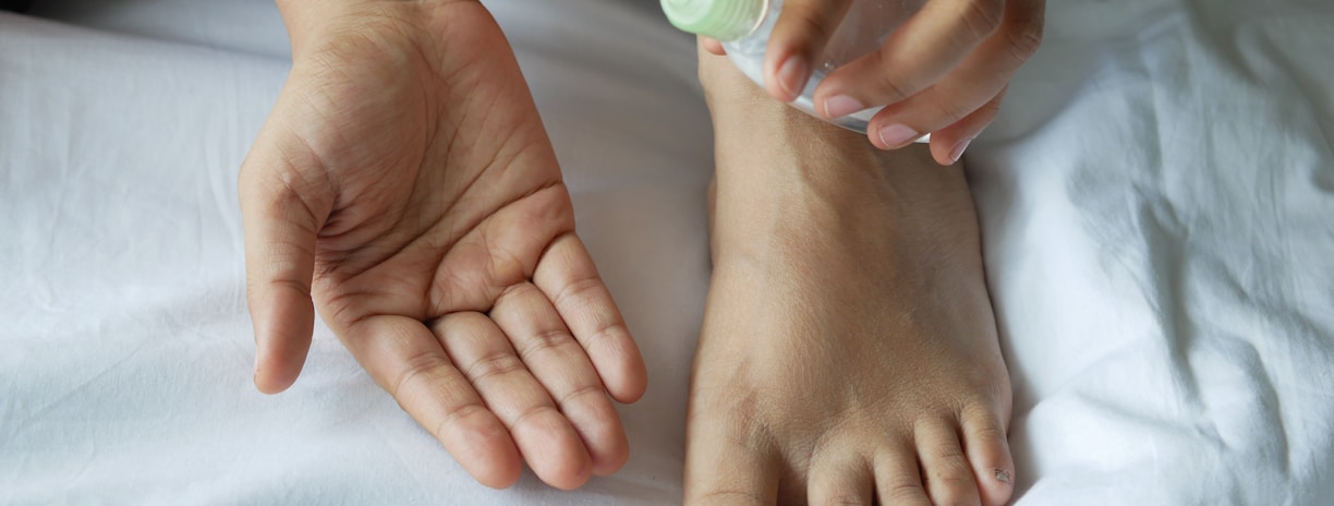 a person with a bottle on their foot on a bed