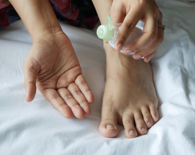 a person with a bottle on their foot on a bed