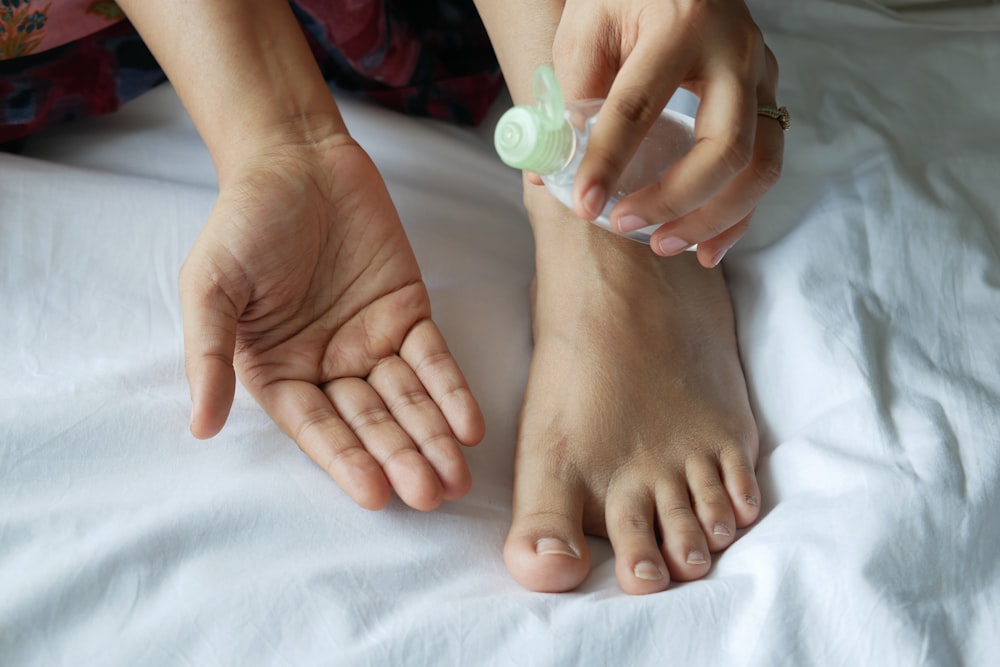 une personne avec une bouteille sur le pied sur un lit