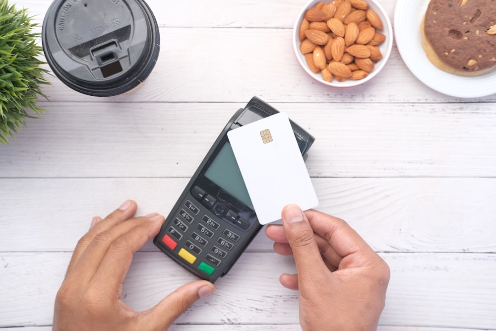 uma pessoa segurando um cartão de crédito ao lado de uma calculadora