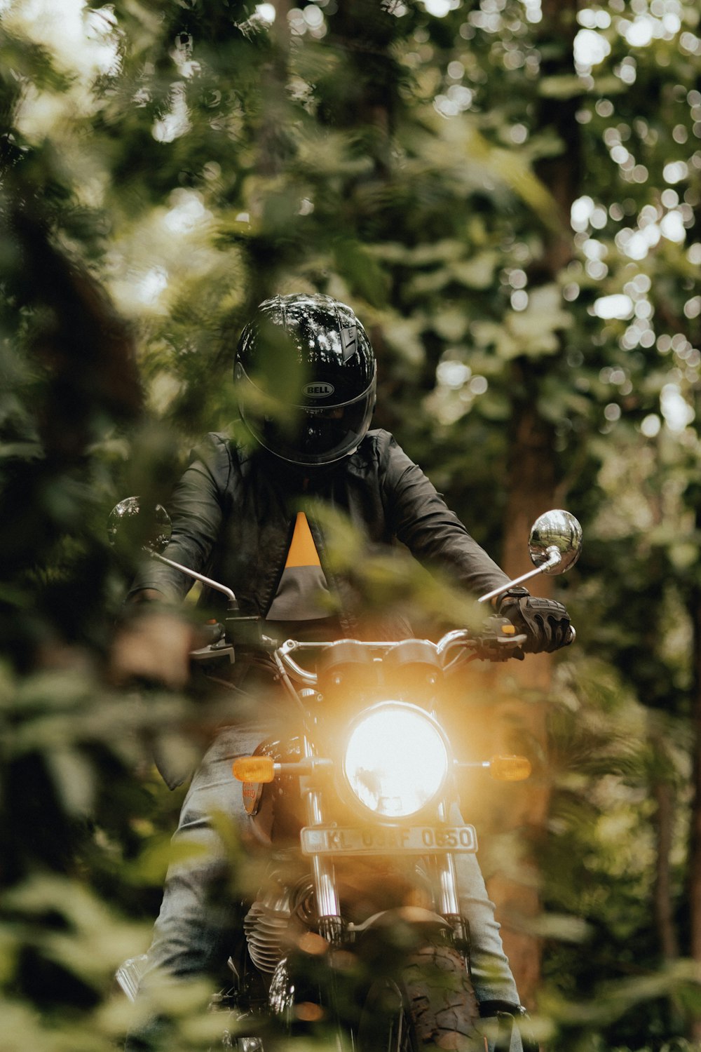 Un uomo in sella a una motocicletta attraverso una foresta