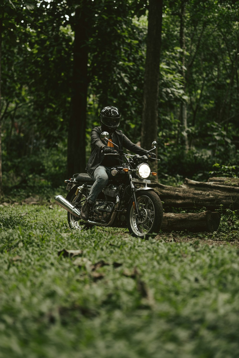 a man riding a motorcycle through a lush green forest