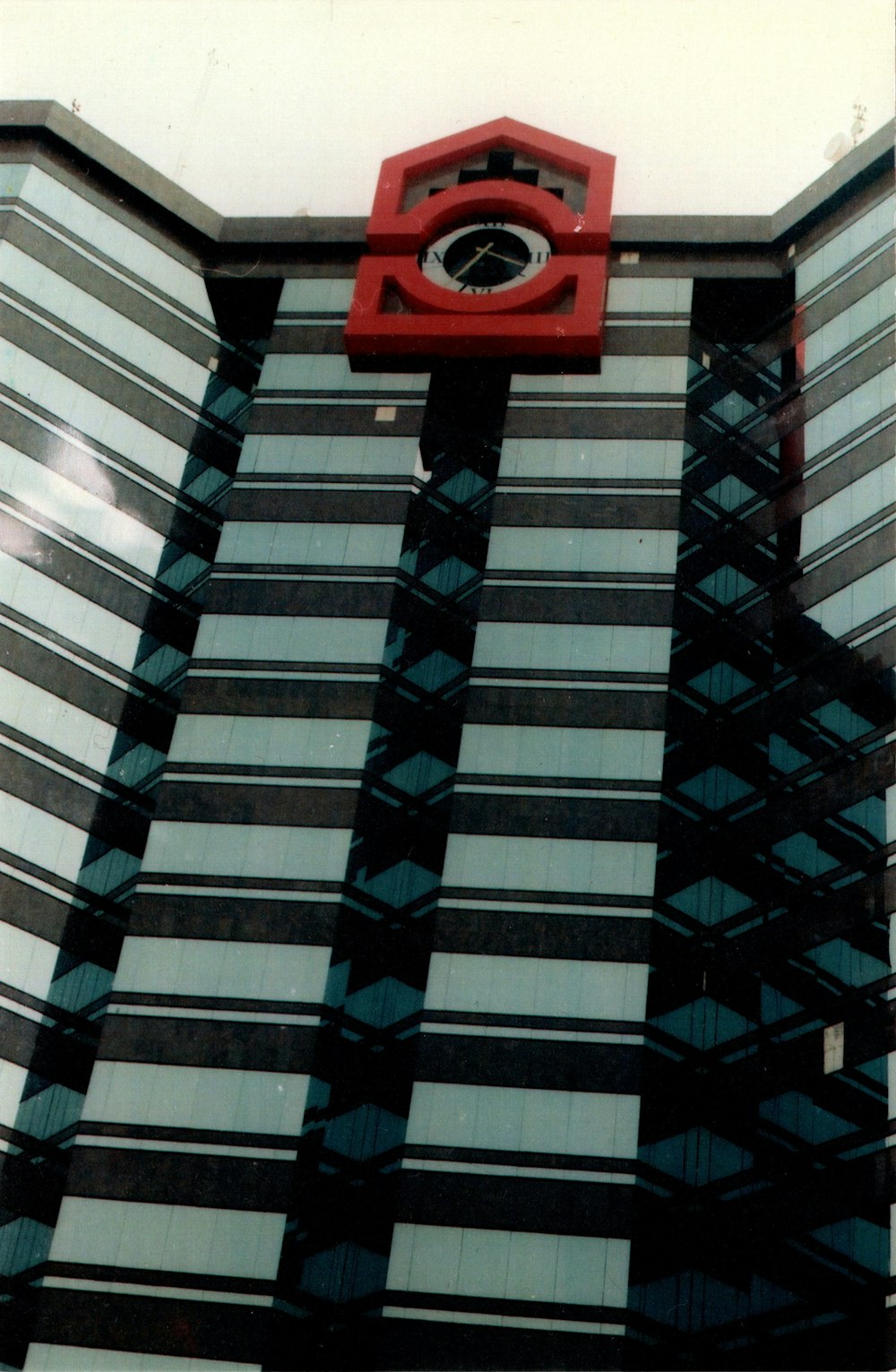 Un reloj rojo en el costado de un edificio alto