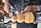 Hands operating a wood lathe, meticulously crafting and shaping a piece of wood amidst flying wood shavings.