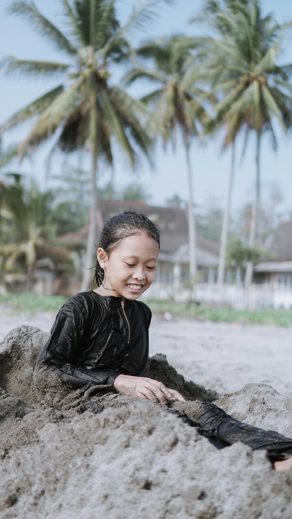 a young girl sitting in the sand on a beach