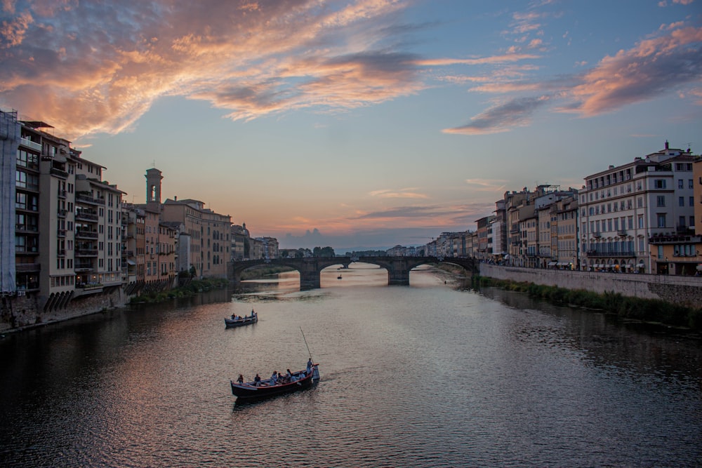 a couple of boats floating down a river next to tall buildings