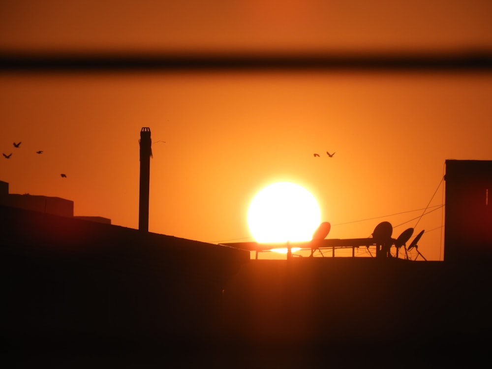 the sun is setting over a rooftop with a table and chairs