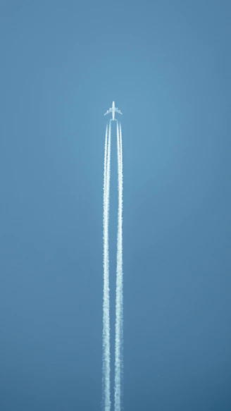 an airplane flying in the sky leaving a trail of smoke behind it