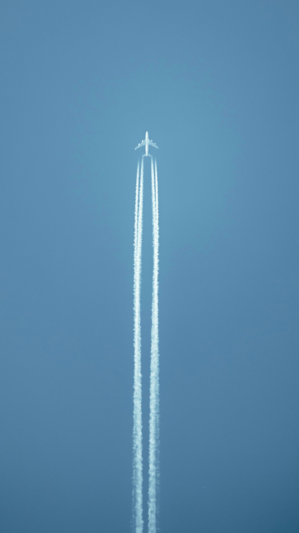 an airplane flying in the sky leaving a trail of smoke behind it