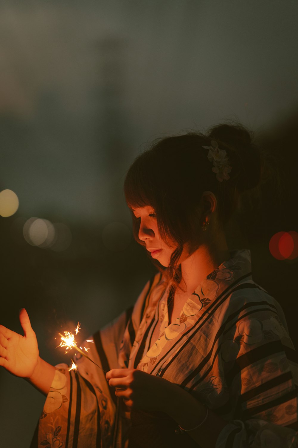 a woman holding a lit sparkler in her hand