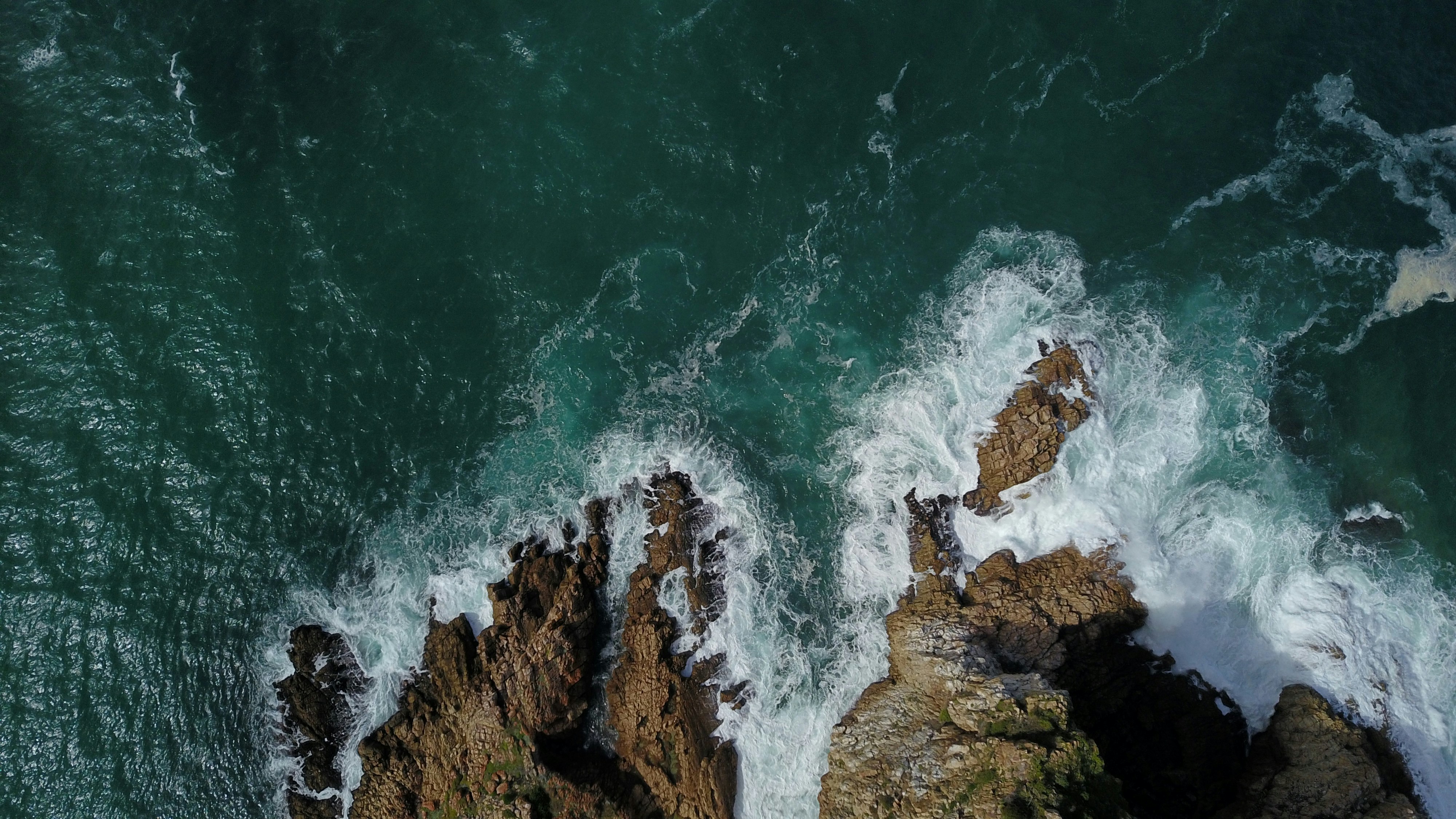 an aerial view of the ocean and rocks