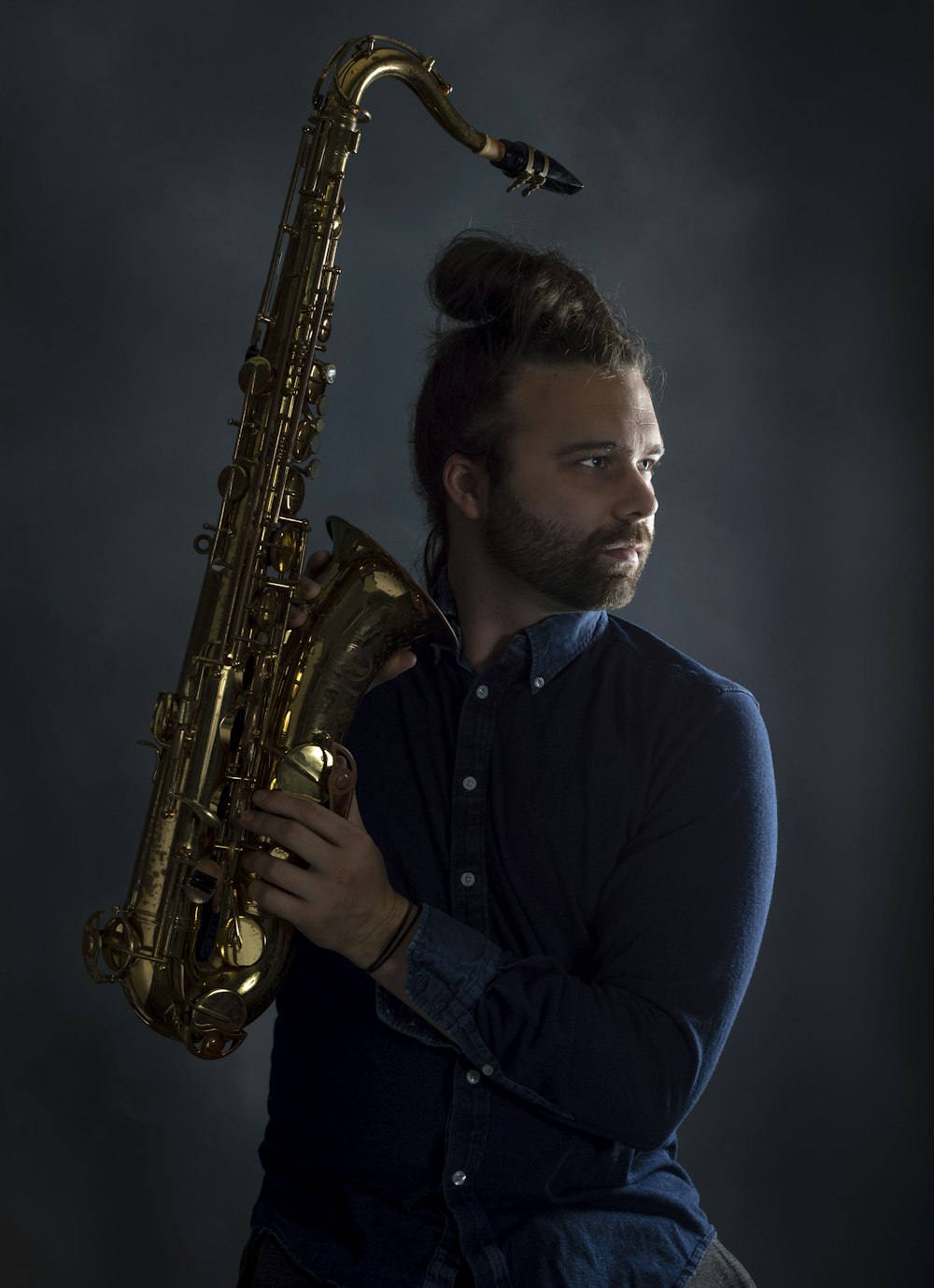 um homem com barba segurando um saxofone