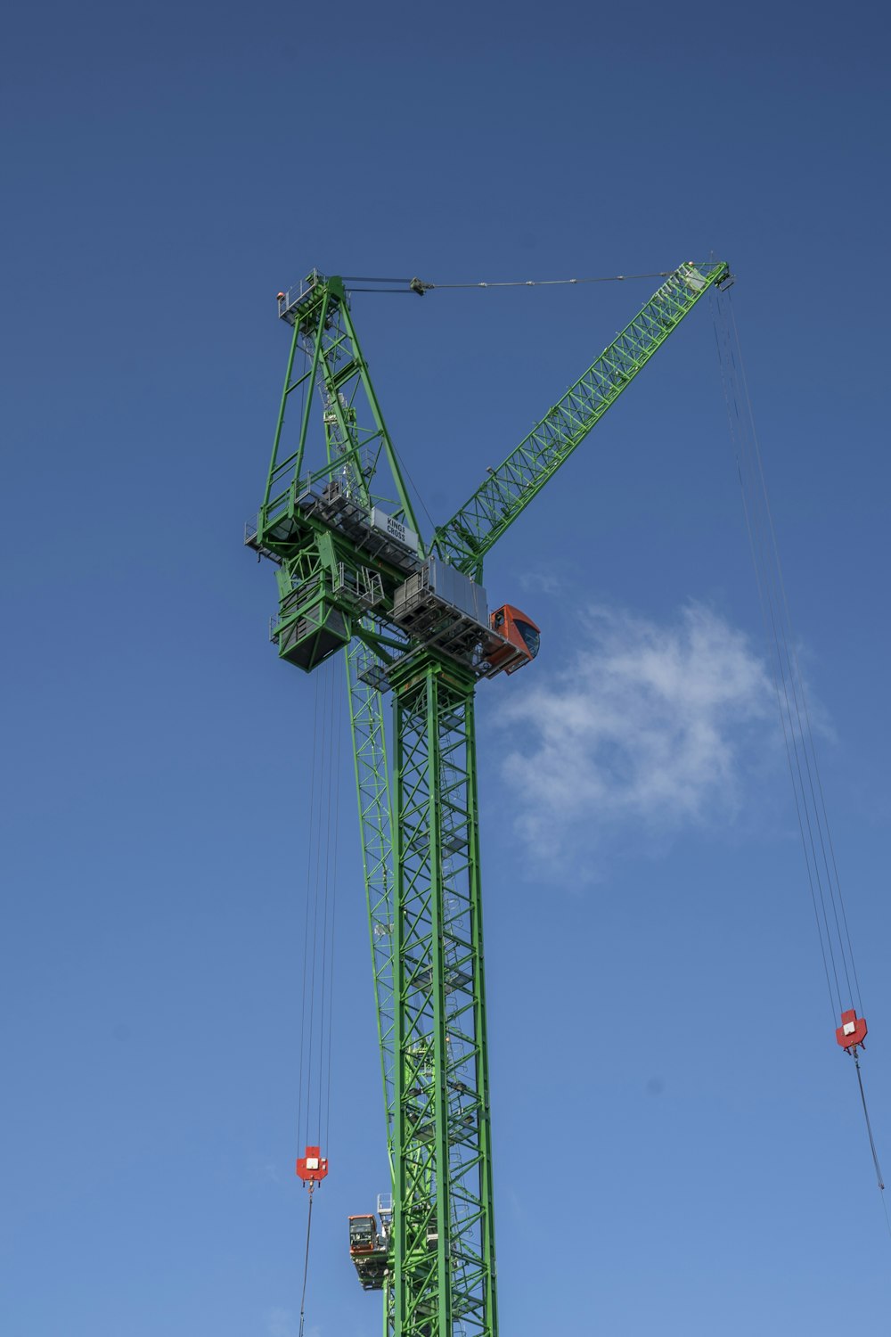 a large green crane sitting on top of a lush green field