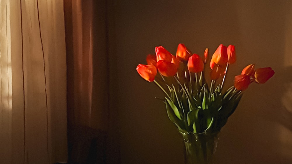 a vase filled with red and orange flowers