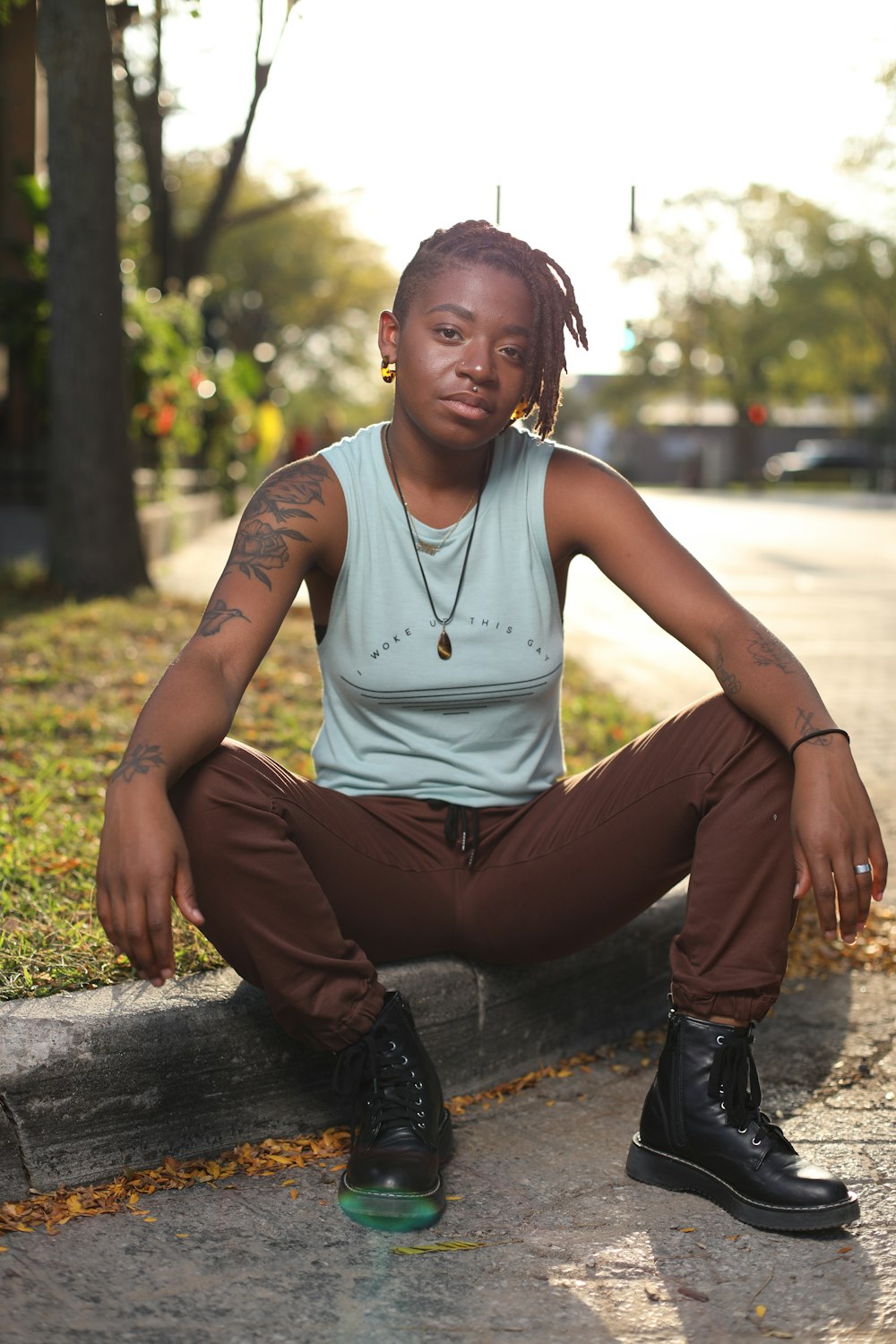 a woman with dreadlocks sitting on a curb