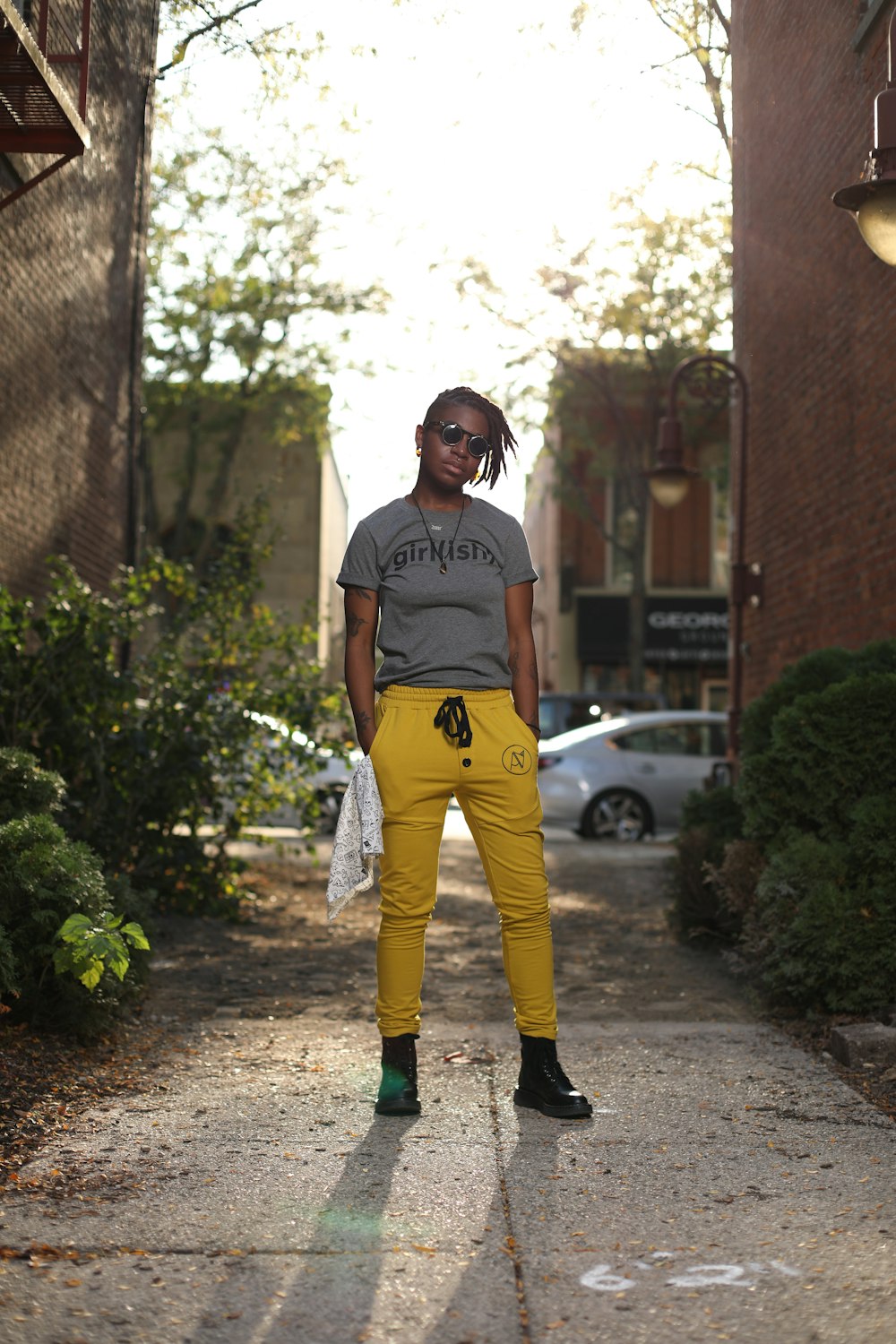 a woman standing on a sidewalk wearing yellow pants