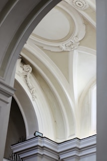 Intricate architectural details featuring elegant arches and ornate moldings. The arches are adorned with classical motifs and reliefs, highlighting the grandeur of the design.
