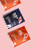 two packets of dog treats on a pink background
