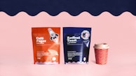 a couple of bags of coffee next to a cup