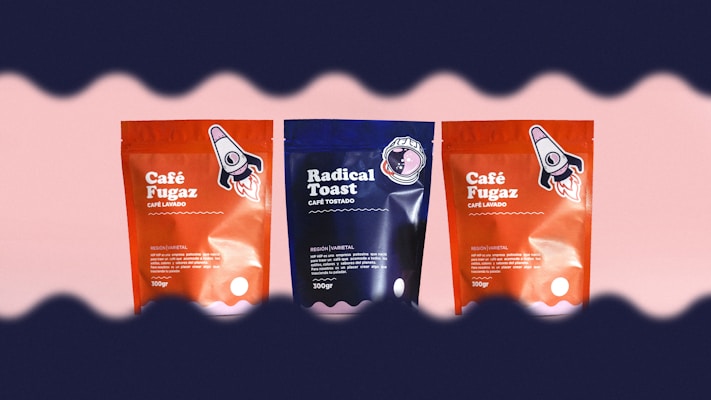 Three coffee packages are arranged side by side against a light pink background. The two outer packages are red with a rocket illustration, labeled 'Caf&eacute; Fugaz'. The center package is blue with a different design, labeled 'Radical Toast'. A wave-like dark border frames the top and bottom edges of the image.