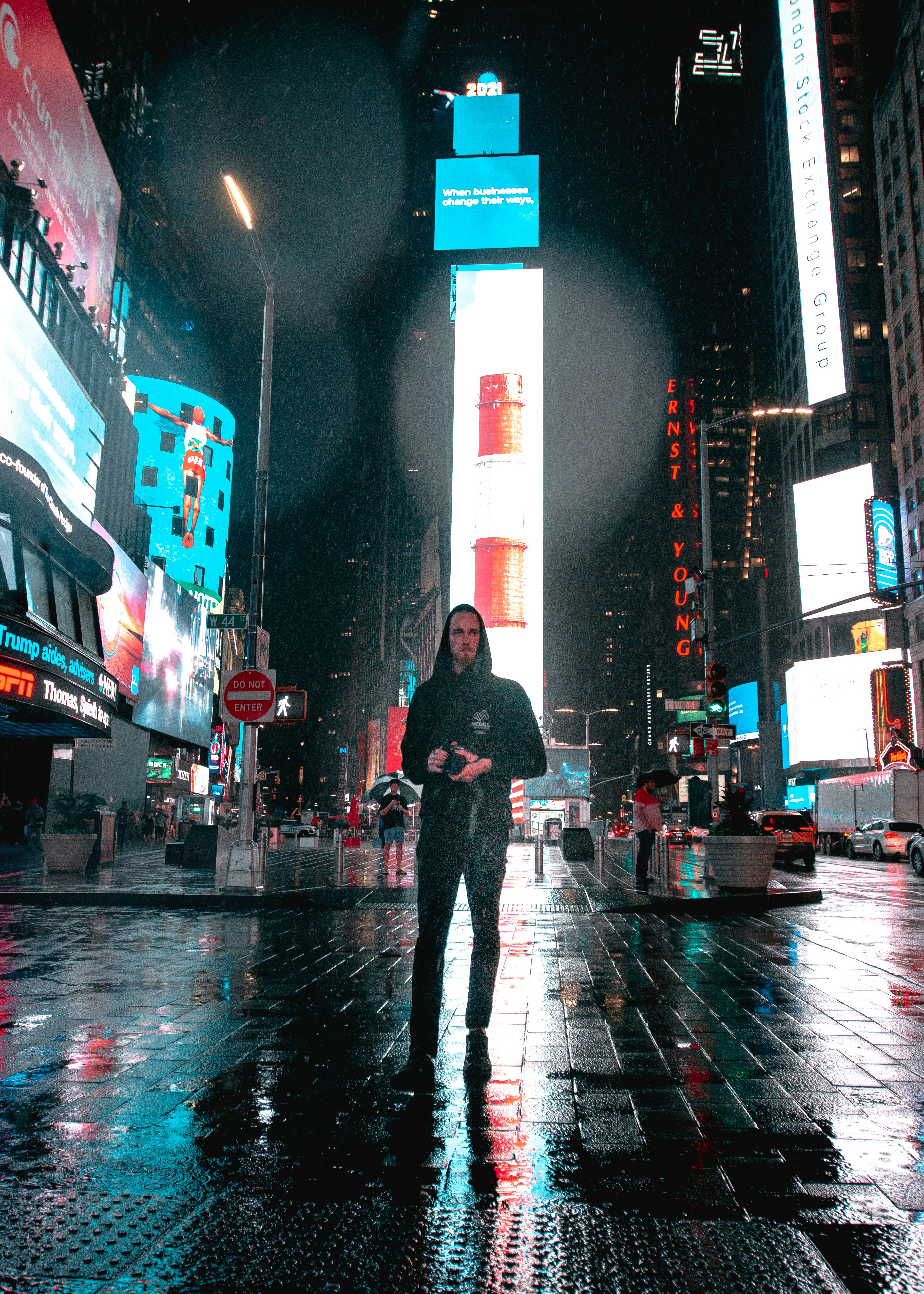 A man standing in the middle of a city at night photo – Free Car Image ...