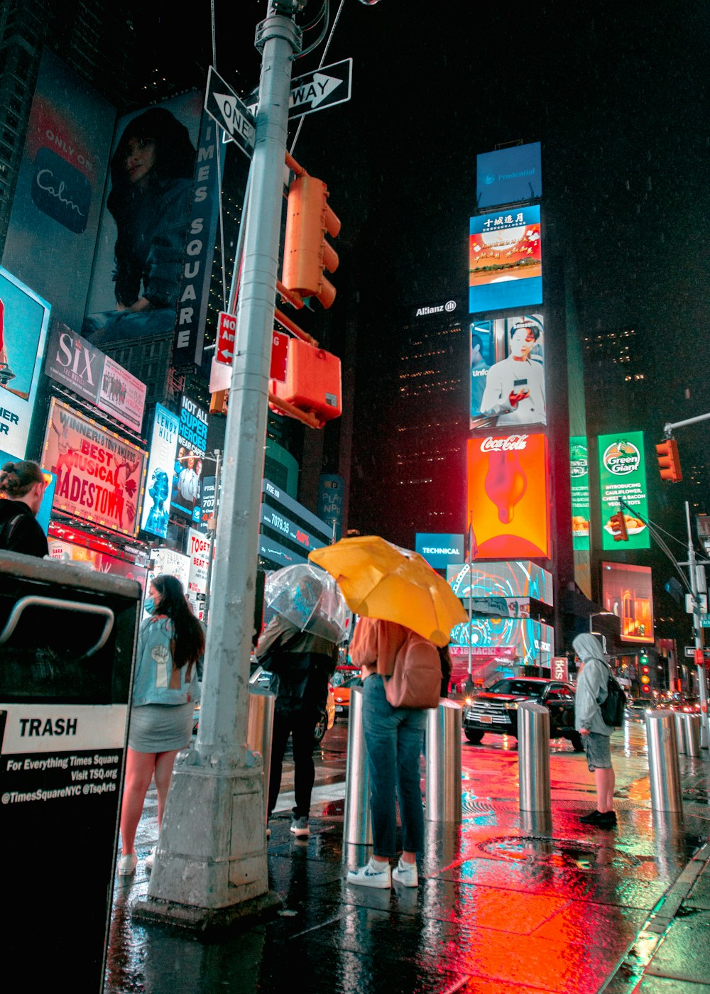 a group of people standing on a street corner holding umbrellas