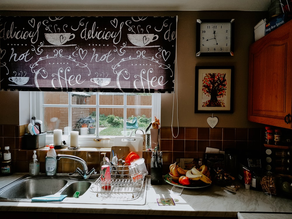 a kitchen sink under a window with a clock above it