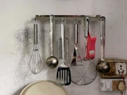 a kitchen wall with a bunch of cooking utensils hanging on it