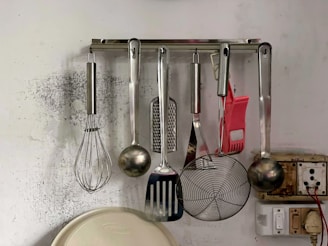 a kitchen wall with a bunch of cooking utensils hanging on it