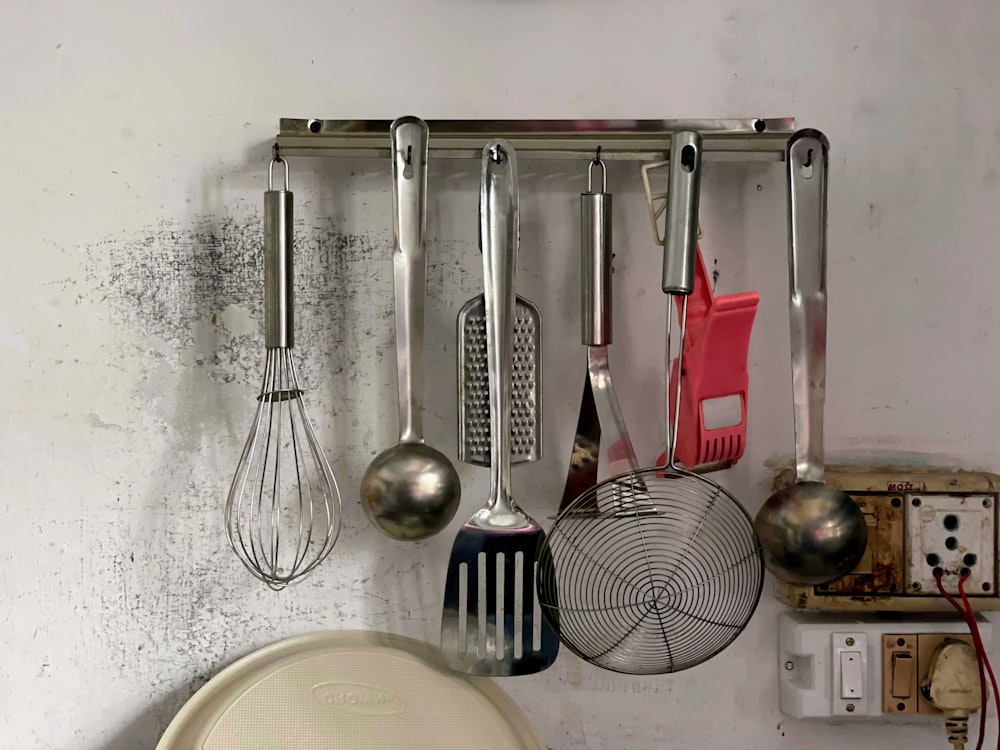 a kitchen wall with a bunch of cooking utensils hanging on it