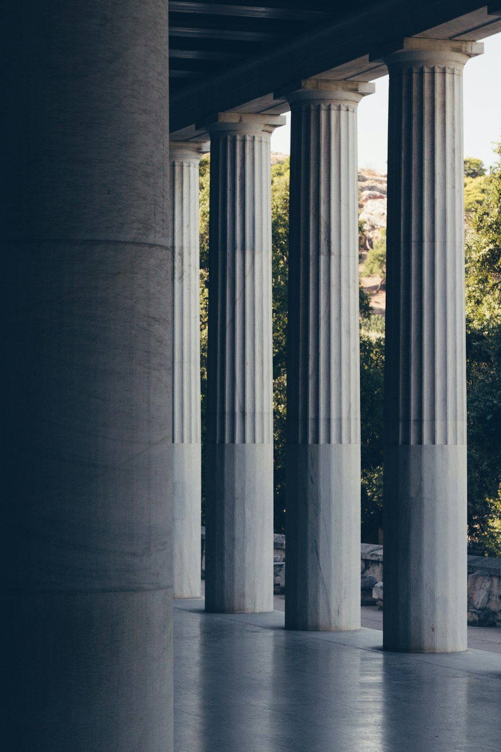 a man riding a skateboard down a sidewalk next to tall pillars