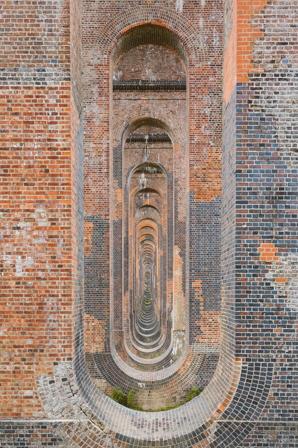 a very long brick tunnel with a clock on the side of it