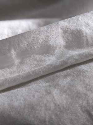 Close-up view of gentle, textured fabric in earthy tones folded neatly on a table.