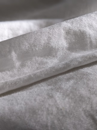 Close-up of silky pajama fabric with gentle folds and stitching details.