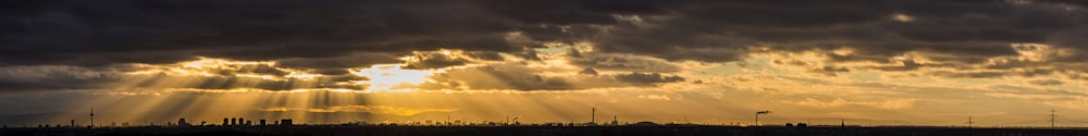 o sol está brilhando através das nuvens sobre um campo