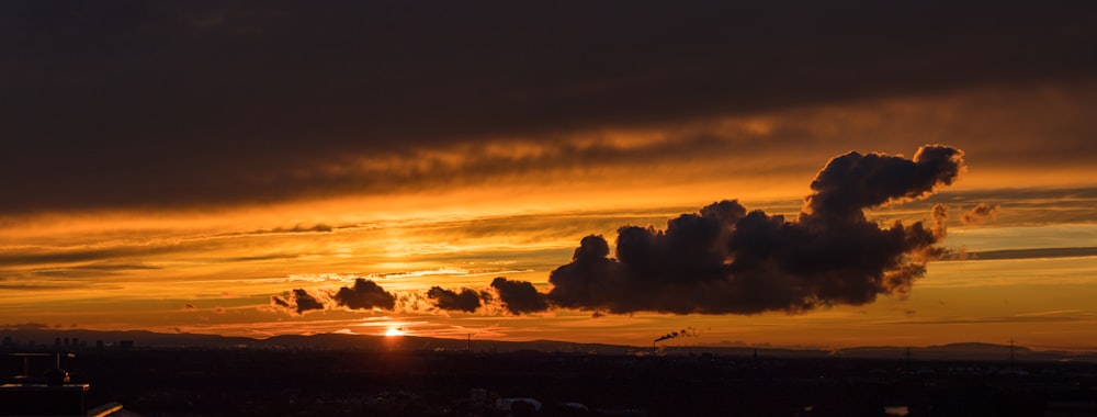 the sun is setting behind a cloud in the sky