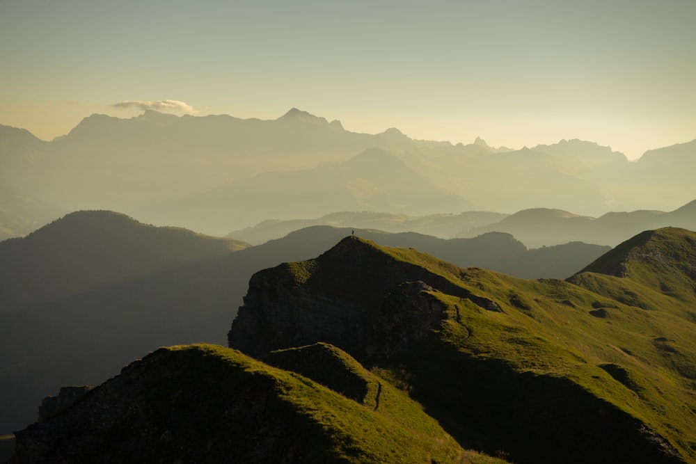 une personne debout au sommet d’une montagne verdoyante