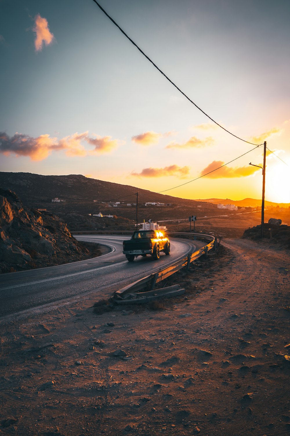 a truck driving down a road at sunset
