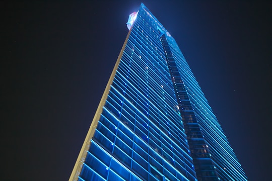 A sleek futuristic office building glowing with blue lights at dusk.
