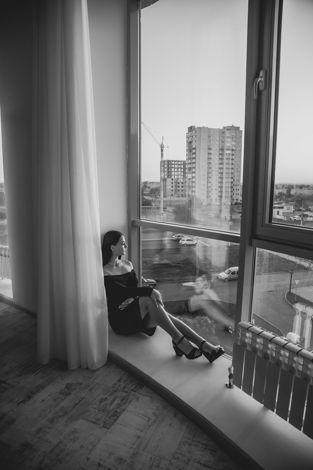 a woman sitting on a window sill looking out the window