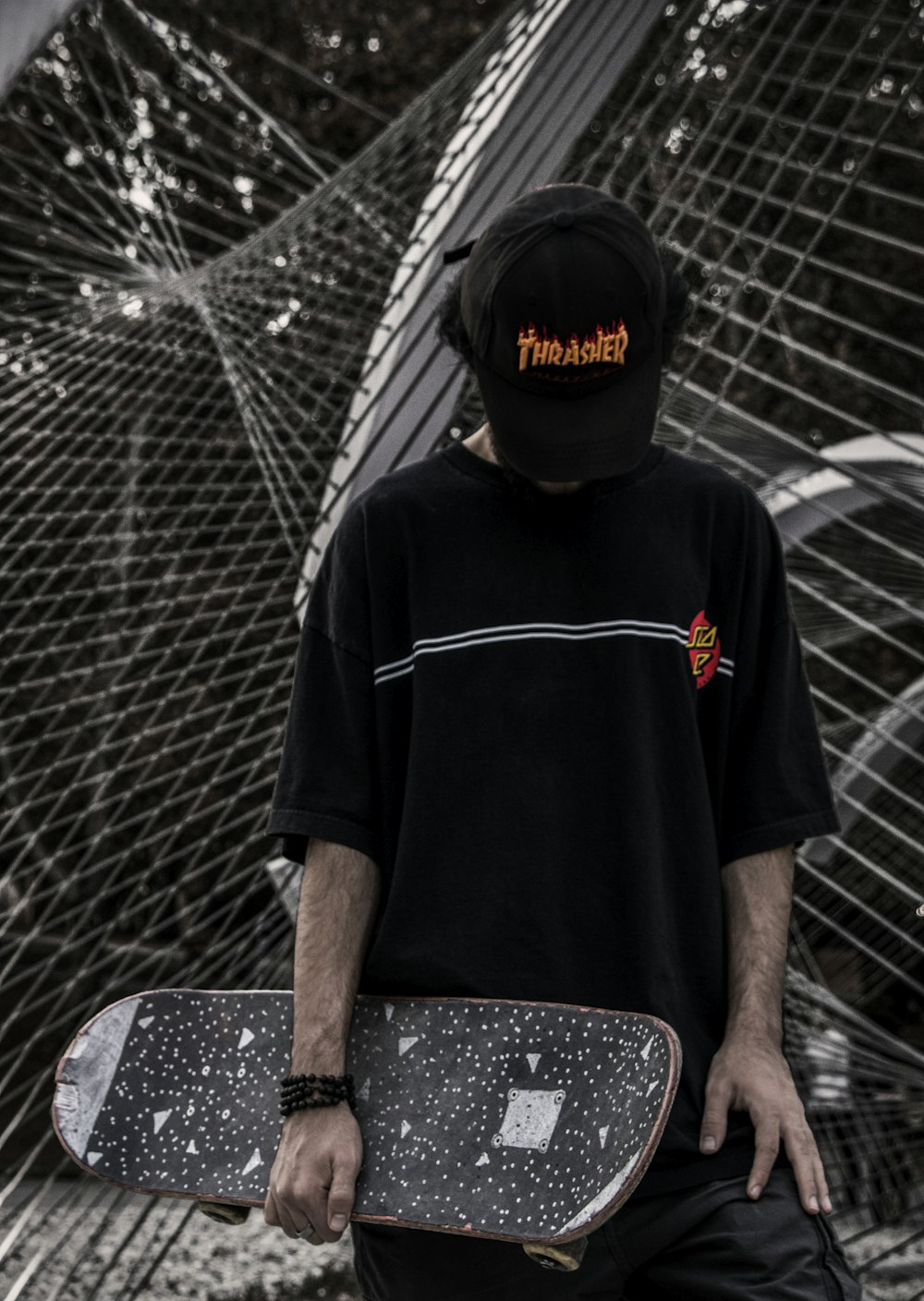 a man holding a skateboard in front of a fence