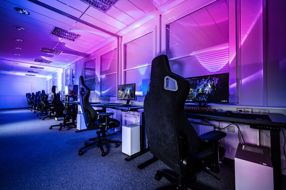 a room filled with lots of computer desks and chairs