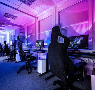 a room filled with lots of computer desks and chairs