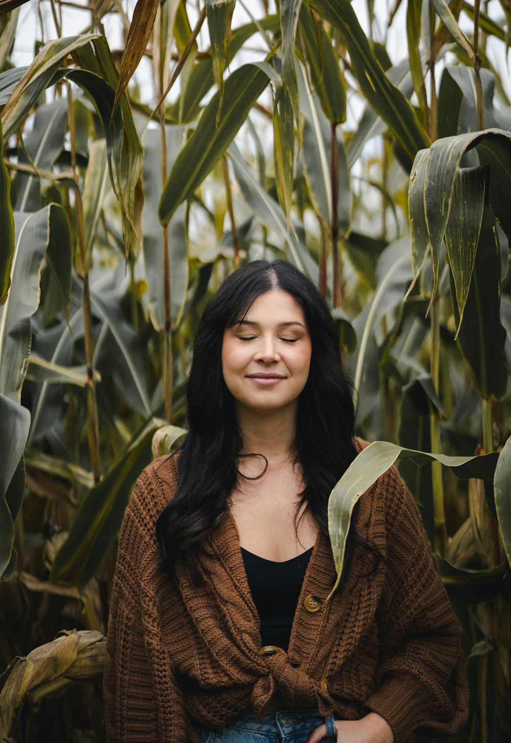 a woman standing in a corn field with her eyes closed
