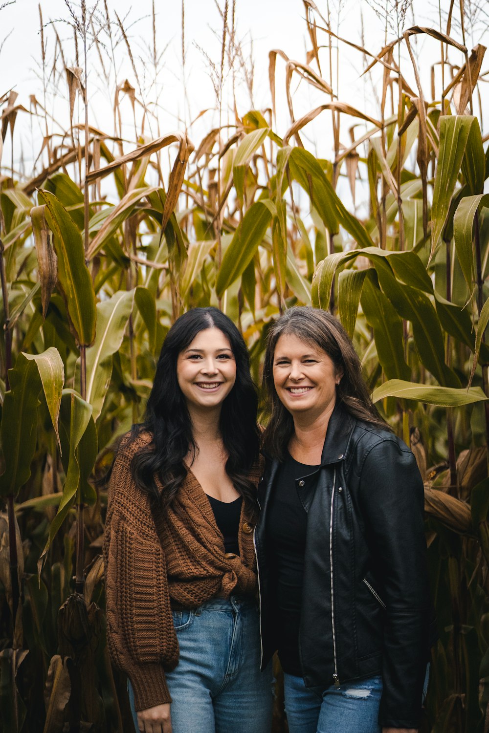 two women standing in front of a corn field