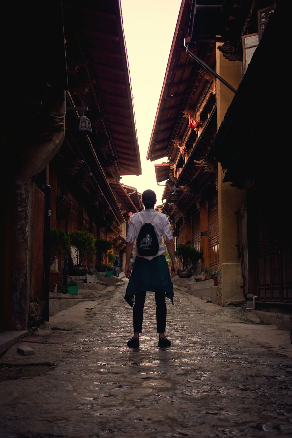 a man walking down a street next to tall buildings