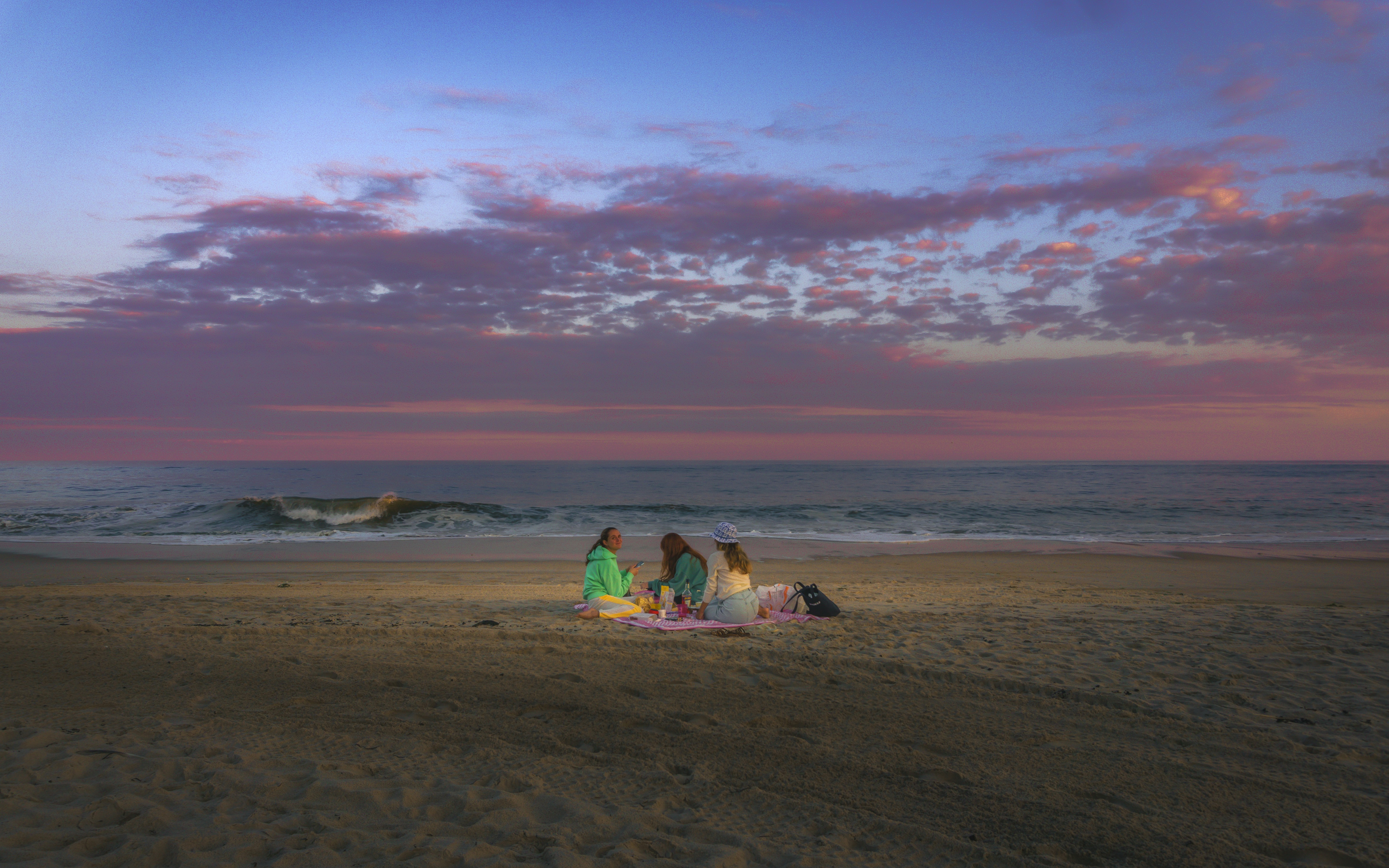 a group of people sitting on top of a sandy beach