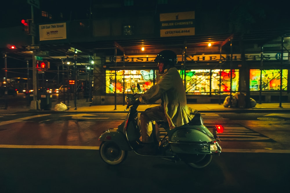 a man riding a scooter down a street at night