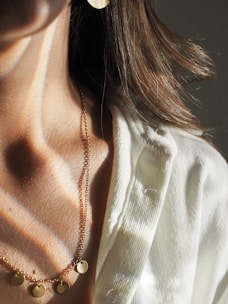 Close-up of a woman's neck and collarbone illuminated by soft golden light against a dark velvet background.