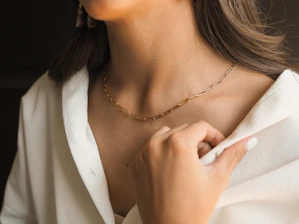 Woman wearing simple, refined gold-plated necklace in warm natural light.
